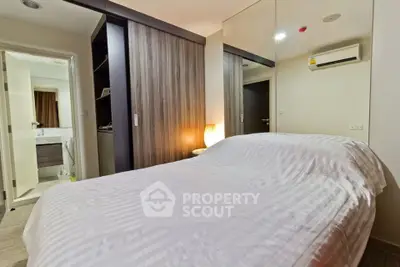 Cozy bedroom with mirrored wardrobe and ensuite bathroom in modern apartment.