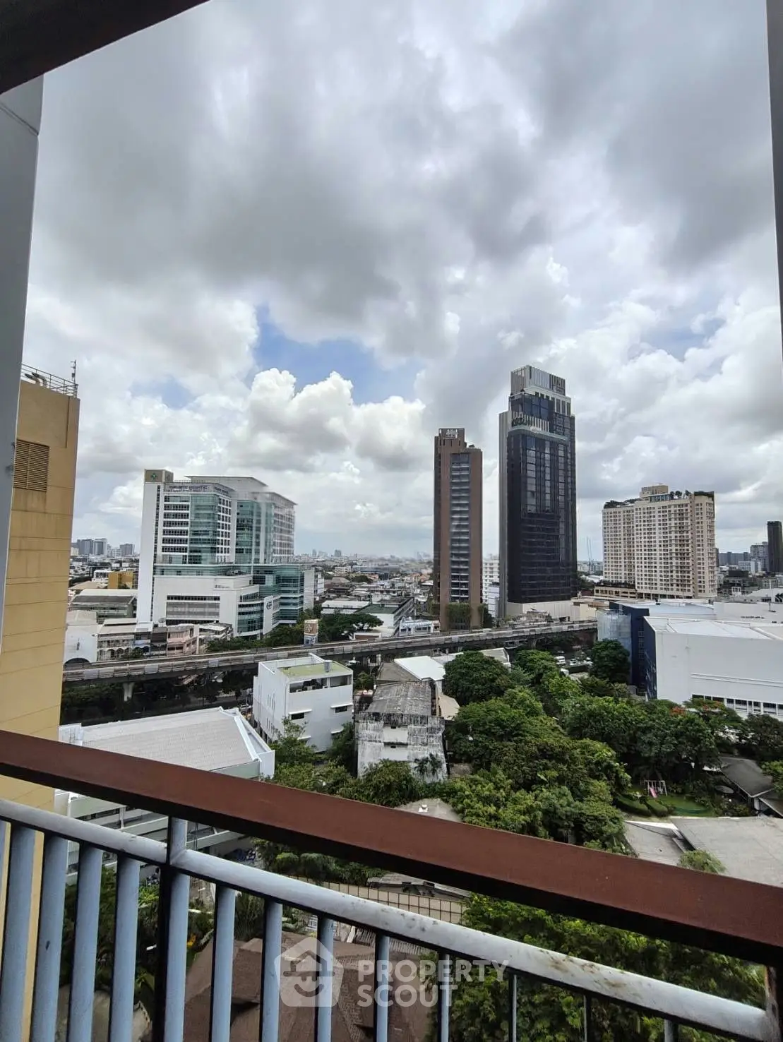 Stunning cityscape view from a high-rise balcony overlooking urban skyline and lush greenery.