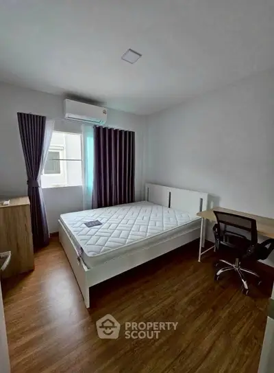 Modern bedroom with wooden flooring, large window, and minimalist furniture.