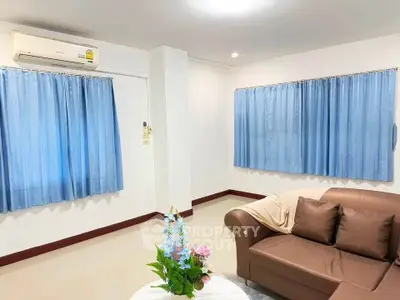 Spacious living room with cozy brown sofa and blue curtains, perfect for relaxation.