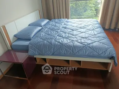 Spacious bedroom with modern bed and large window offering natural light and serene views.