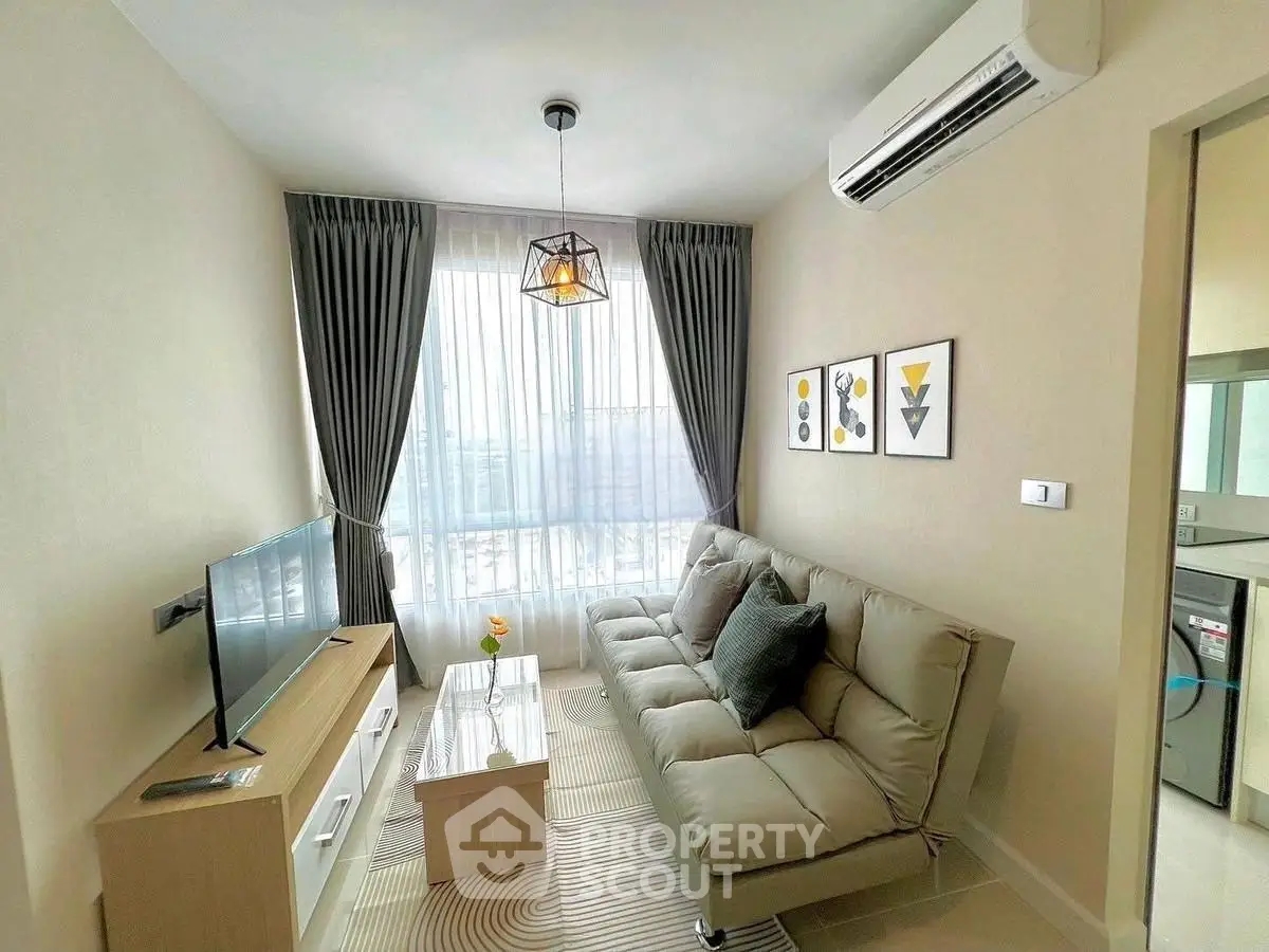 Modern living room with stylish decor, featuring a cozy sofa, wall art, and natural light from large windows.