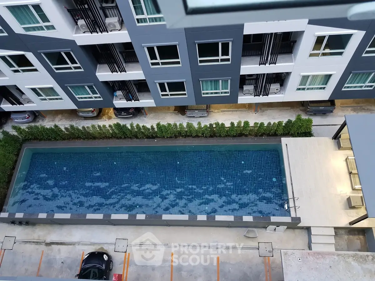 Modern apartment building with a sleek swimming pool view from above, showcasing urban living amenities.