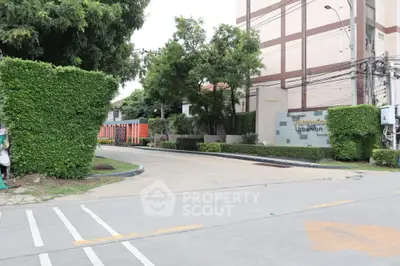 Modern urban building entrance with lush greenery and well-maintained hedges, offering a welcoming atmosphere.