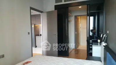 Modern bedroom with sleek design and open closet, adjacent to a contemporary kitchen.