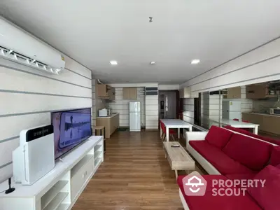 Modern living room with open kitchen, red sofa, and wooden flooring in a stylish apartment.