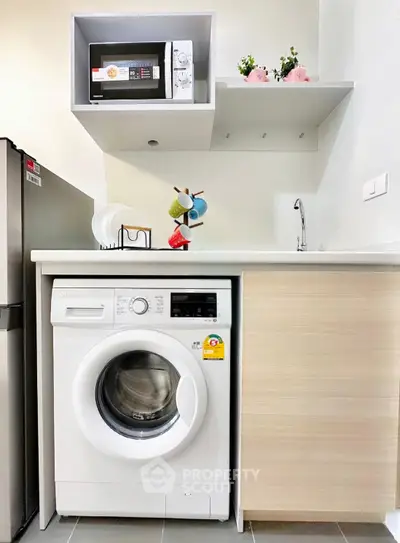 Modern kitchen with washing machine, microwave, and sleek cabinetry