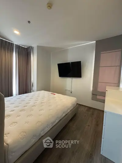 Modern bedroom with sleek design, featuring a wall-mounted TV and large windows for natural light.