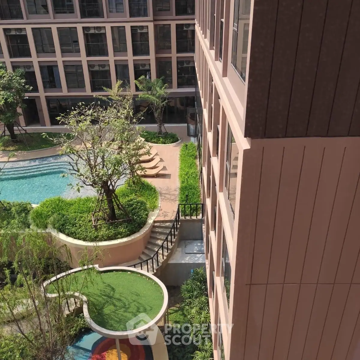 Modern apartment building with lush garden and pool view from upper floor.