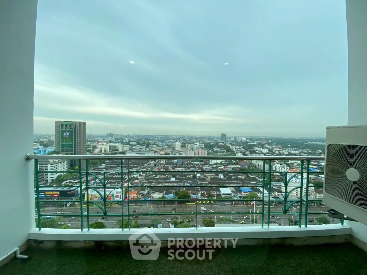 Stunning cityscape view from high-rise balcony with glass railing.