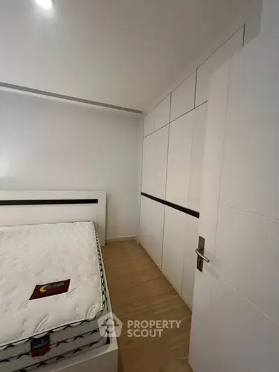 Modern bedroom with sleek white wardrobe and comfortable mattress