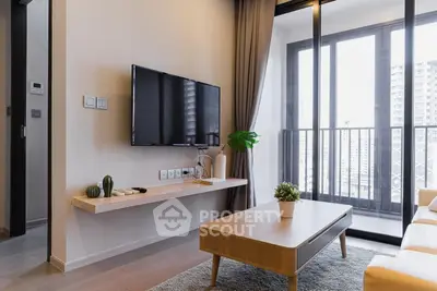 Modern living room with sleek TV setup and balcony view in urban apartment.