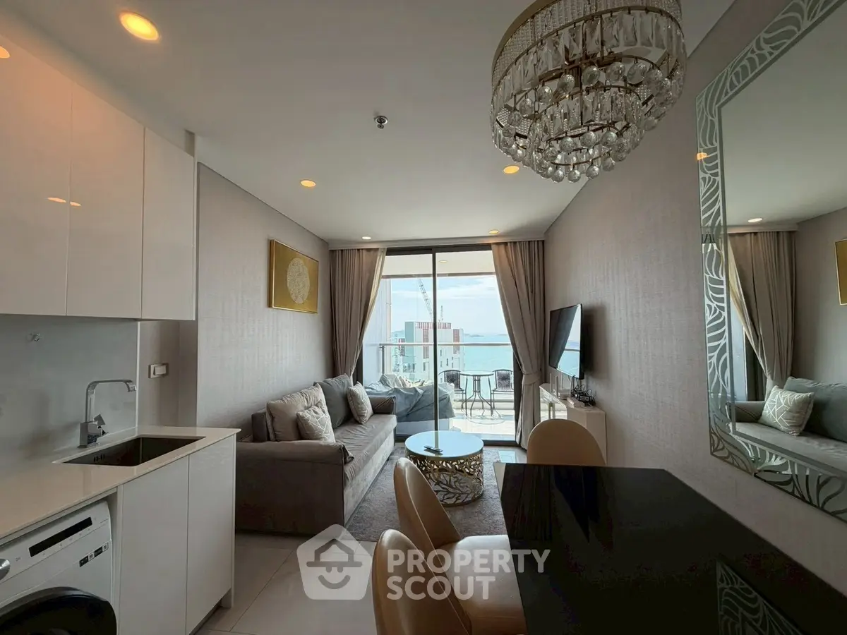 Luxurious modern living room with ocean view, elegant chandelier, and stylish decor in a high-rise apartment.