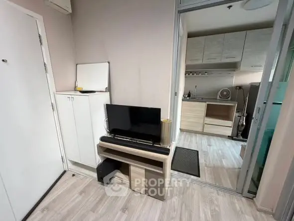 Modern compact living room with sleek TV stand and adjacent kitchen area.