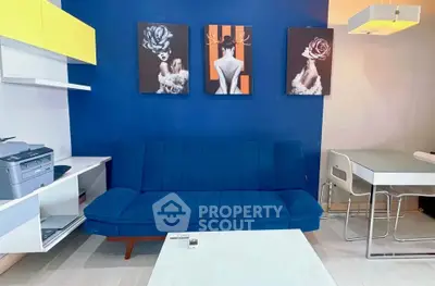 Modern living room with blue sofa, stylish artwork, and sleek furniture design.