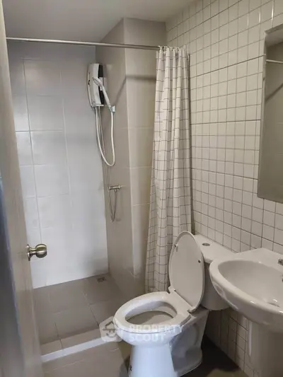 Modern bathroom with shower, toilet, and sink in a tiled setting.