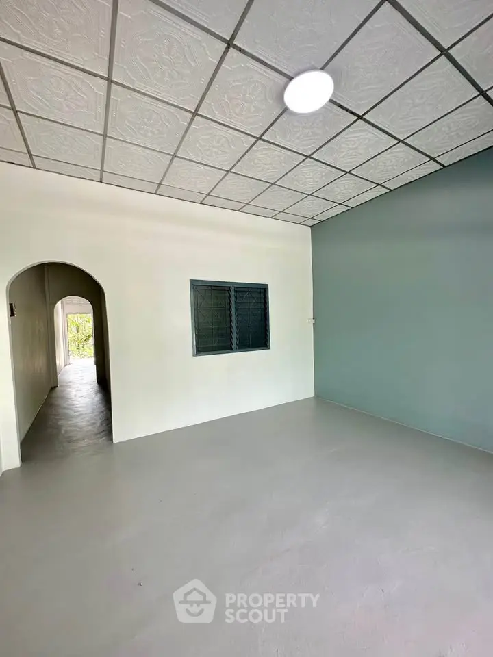 Spacious empty room with arched hallway and modern ceiling design, perfect for customization.