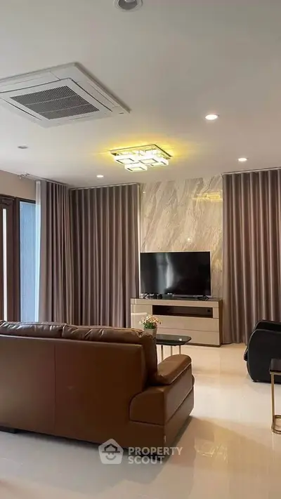 Luxurious living room with modern decor, leather sofa, and large TV, perfect for relaxation and entertainment.