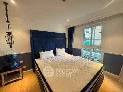 Spacious bedroom with elegant decor and large window for natural light.