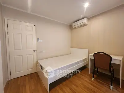 Cozy bedroom with single bed, desk, and air conditioning in modern apartment.