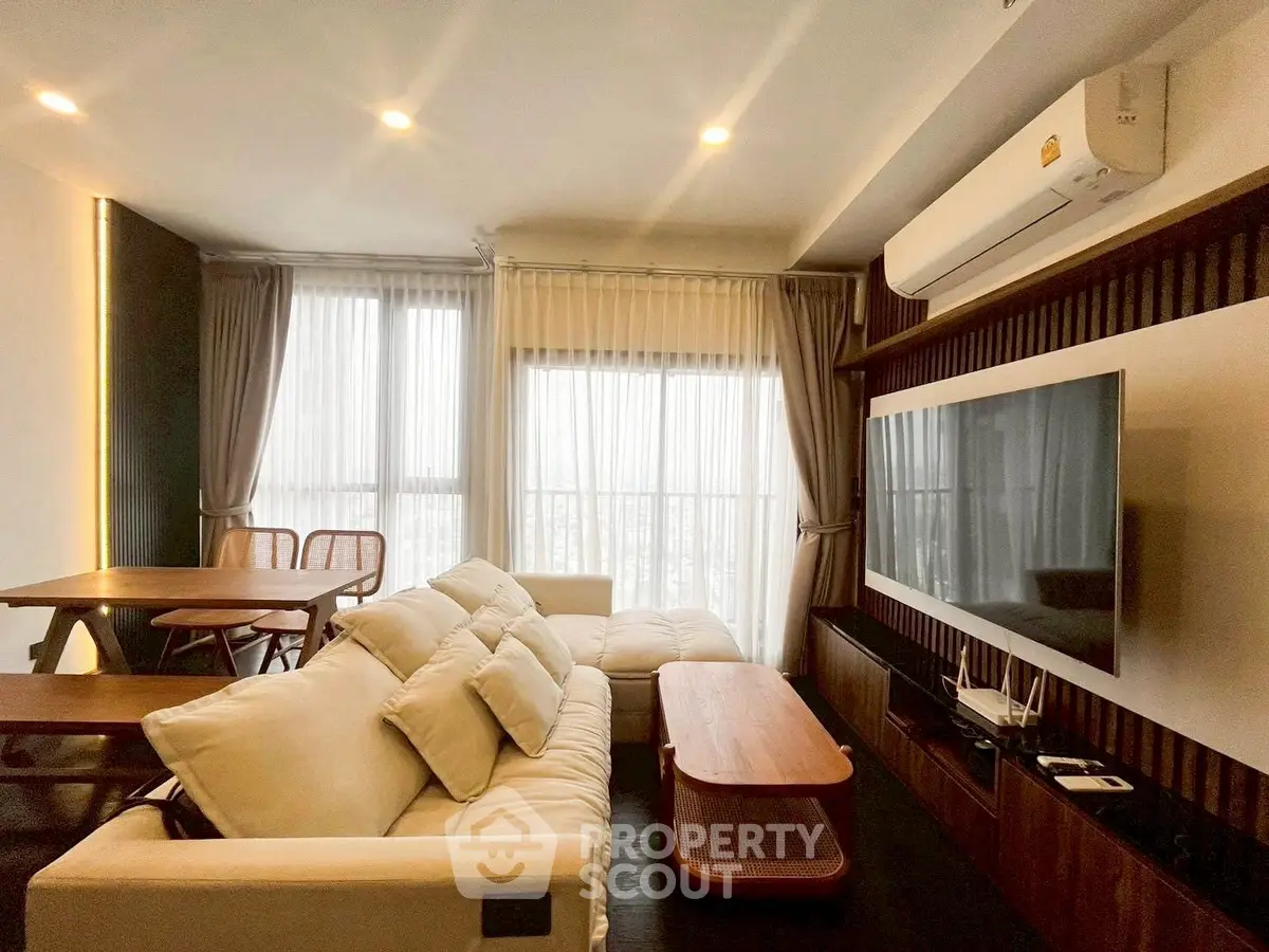 Modern living room with cozy sofa, large TV, and elegant dining area.