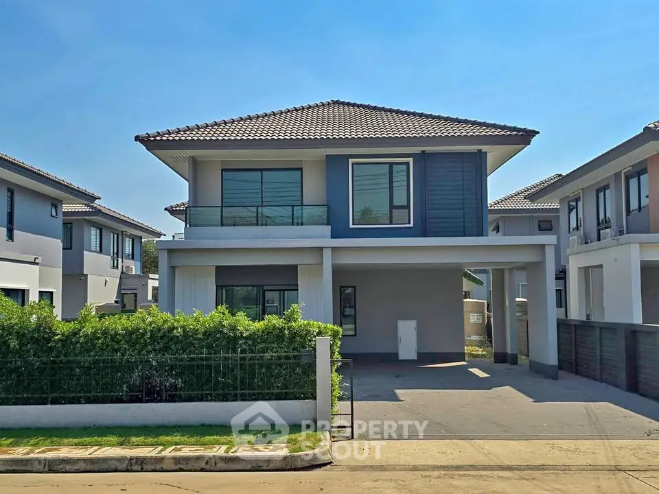 Modern two-story house with sleek design and spacious driveway in suburban neighborhood.