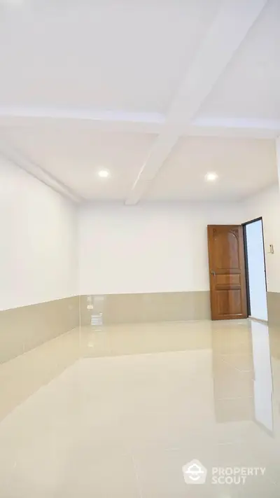 Spacious empty room with glossy tiled flooring and wooden door