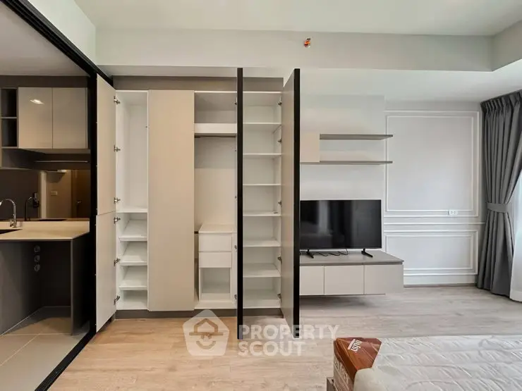 Modern apartment interior with open closet, sleek kitchen, and cozy living area.