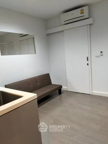 Modern minimalist living room with sleek sofa and air conditioning unit.