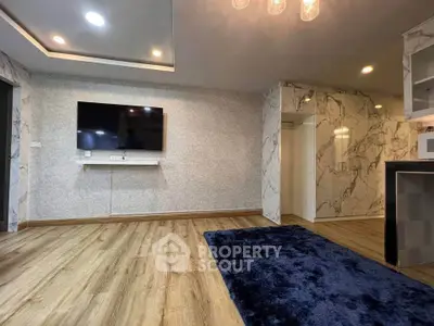 Modern living room with wood flooring, wall-mounted TV, and stylish marble accents.