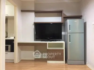 Modern living room with sleek TV unit and stainless steel fridge, showcasing contemporary design and functionality.