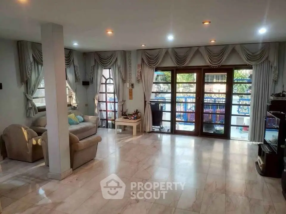 Spacious living room with elegant curtains and large windows opening to a balcony.