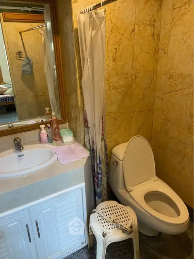 Cozy bathroom with marble walls, modern sink, and toilet in a stylish home.