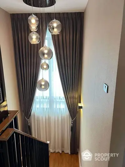 Elegant staircase with modern pendant lighting and floor-to-ceiling curtains