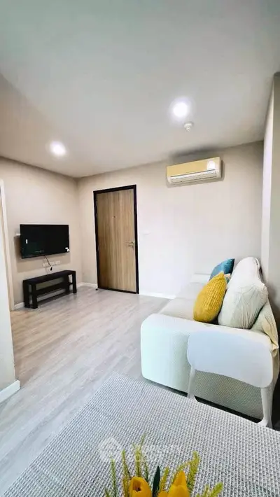 Modern living room with cozy sofa, wall-mounted TV, and air conditioning in a stylish apartment.