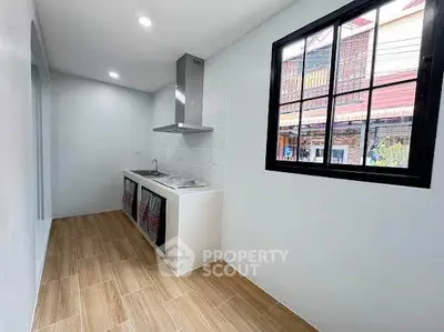 Modern kitchen with sleek design and wooden flooring, featuring a gas stove and ample natural light.