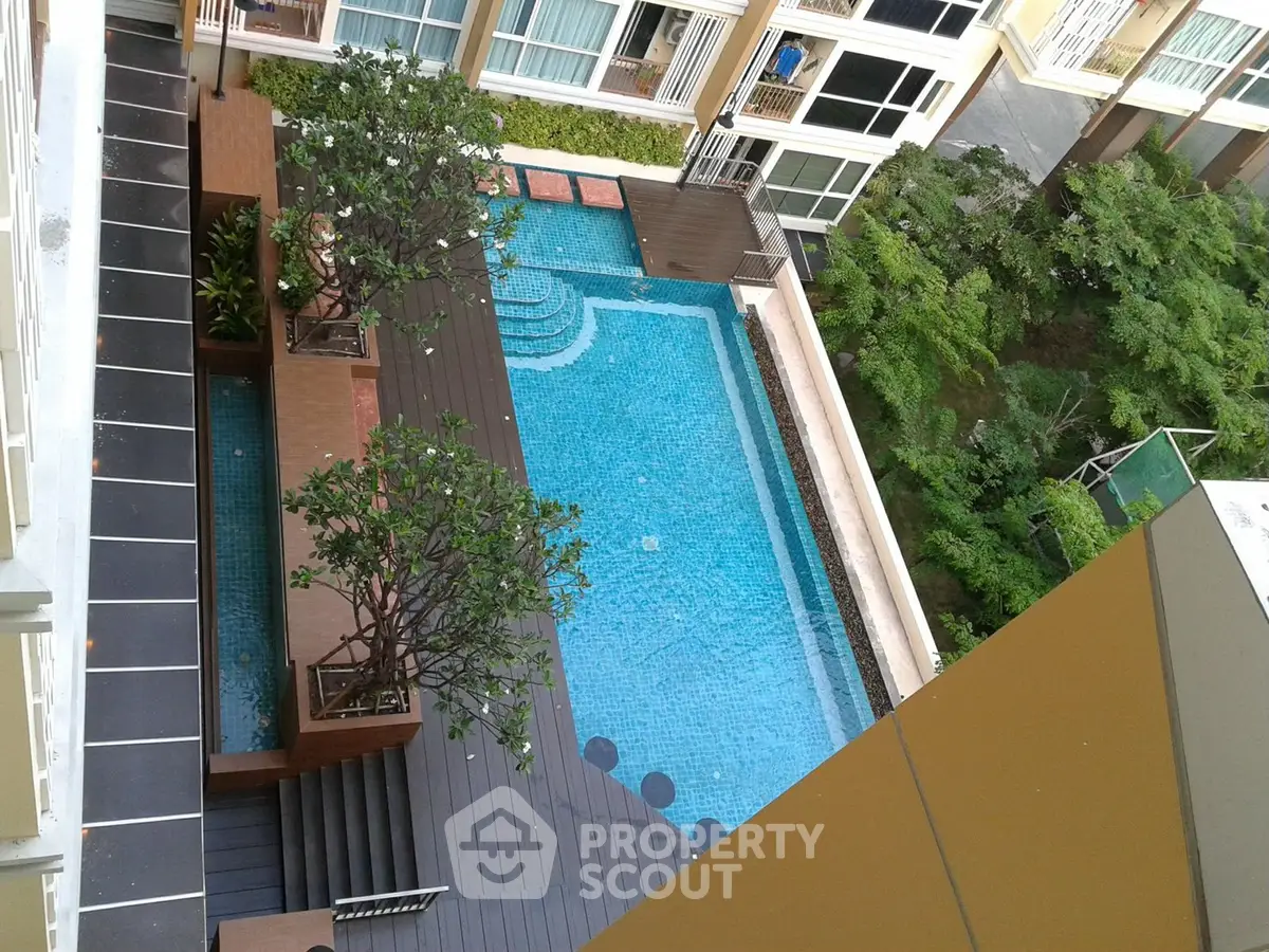 Stunning aerial view of a modern apartment complex with a luxurious swimming pool and lush greenery.