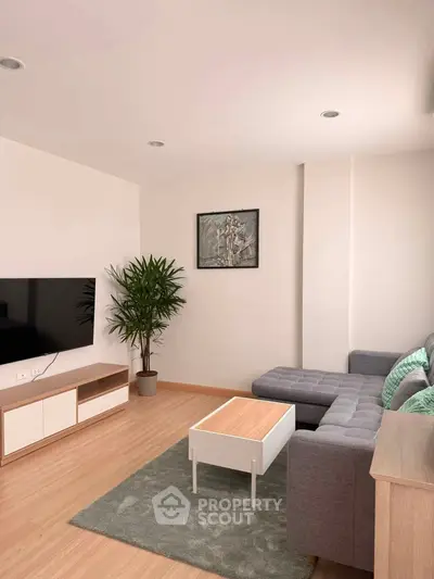 Modern living room with sleek furniture and wall-mounted TV, perfect for relaxation and entertainment.
