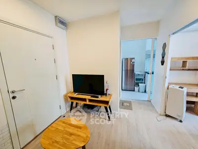 Modern apartment interior with TV, wooden furniture, and open kitchen layout.