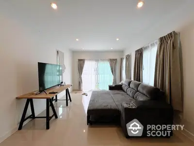 Spacious living room with modern sofa and large TV, perfect for relaxation and entertainment.