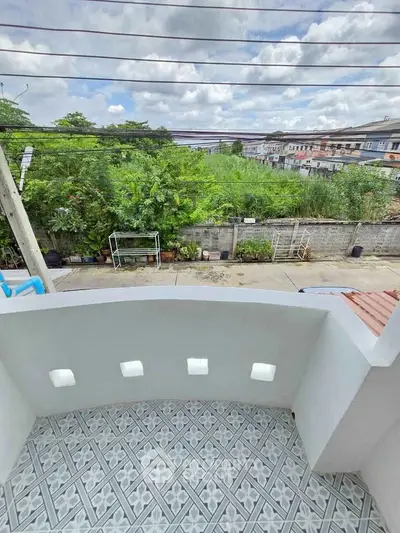 Charming balcony with patterned tiles overlooking lush greenery and neighborhood view.