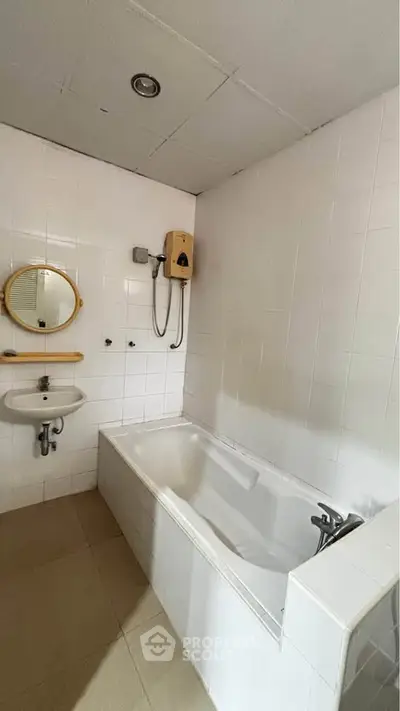 Spacious bathroom with bathtub and modern fixtures in a tiled setting.