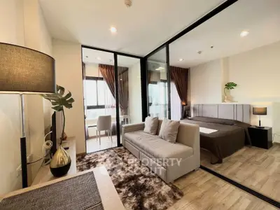 Modern studio apartment with cozy living area and stylish bedroom separated by glass partition.