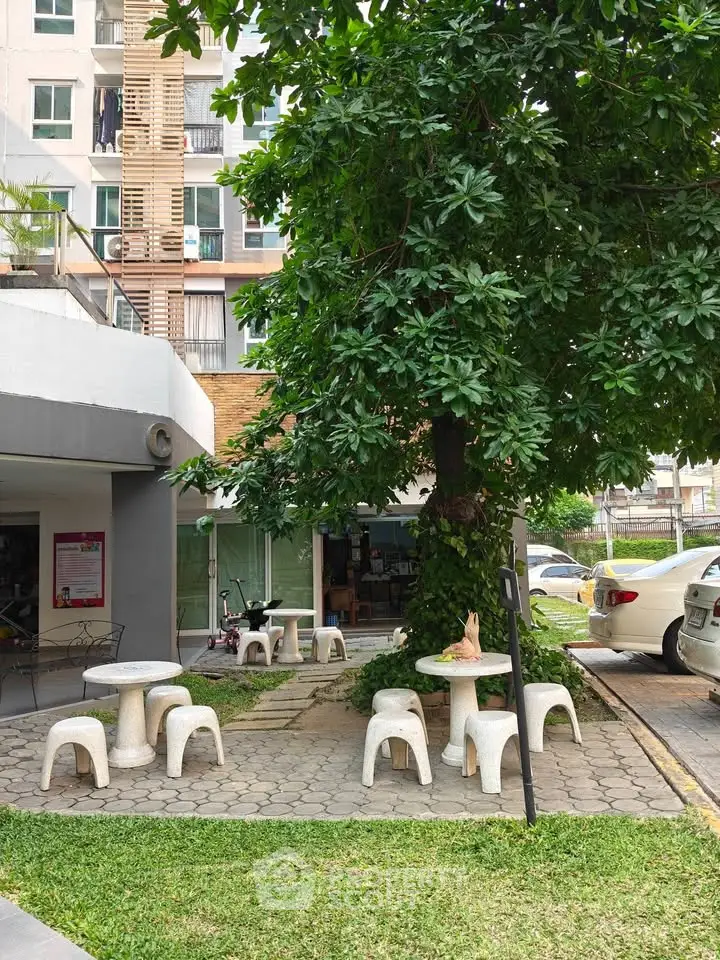 Charming outdoor seating area with lush greenery in a modern residential complex.