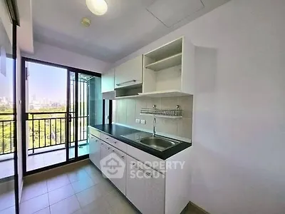 Modern kitchen with balcony view in high-rise apartment, featuring sleek cabinetry and ample natural light.