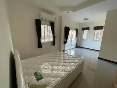 Spacious bedroom with large windows and natural light, featuring a comfortable bed and modern decor.