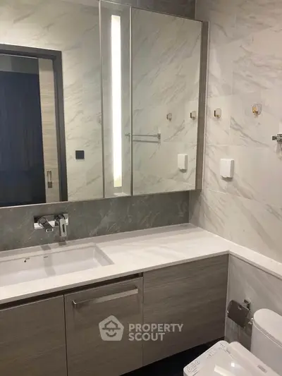 Modern bathroom with sleek vanity and illuminated mirror in luxury apartment.
