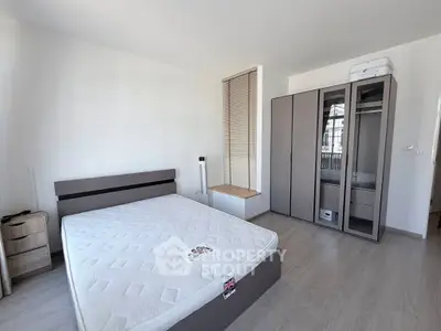 Spacious bedroom with modern furniture and ample natural light, perfect for comfortable living.