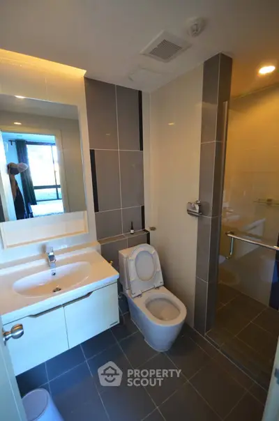 Modern bathroom with sleek design, featuring a glass shower and stylish vanity in a contemporary apartment.