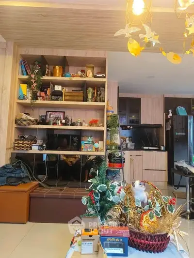 Charming living room with built-in wooden shelves and modern kitchen in open layout.